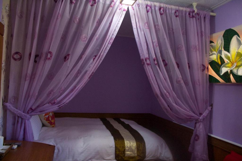 a bedroom with a bed with pink curtains at 文風小築Wen-Feng House-免費停車 in Kenting