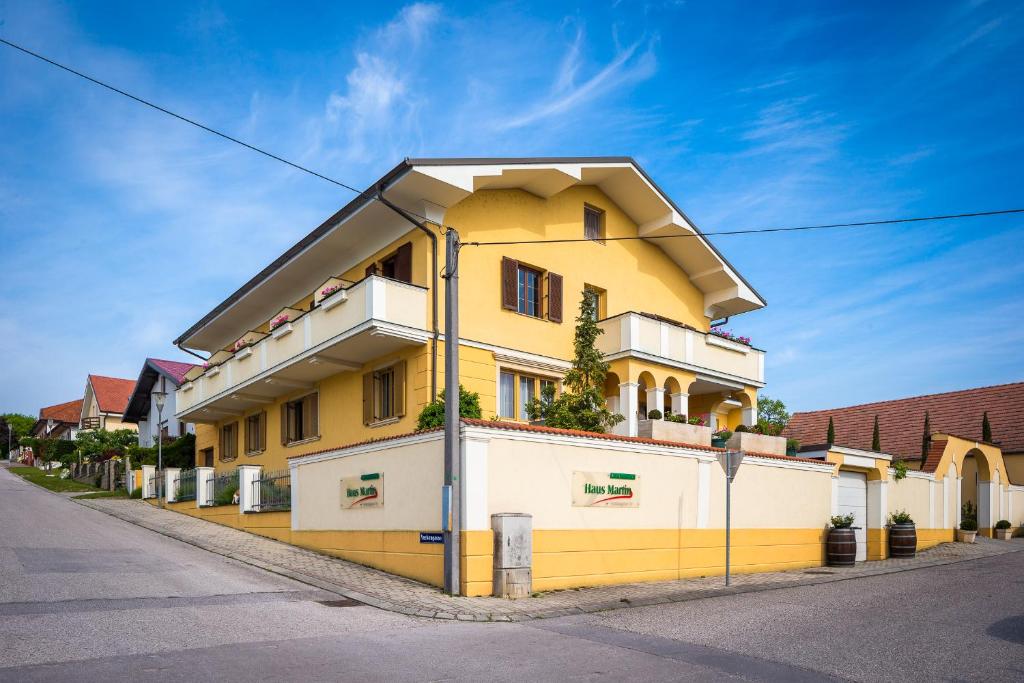 un edificio amarillo y blanco al lado de una calle en Haus Martin - Schneeberger, en Mörbisch am See