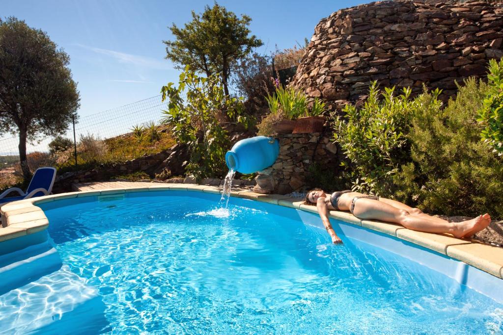 una mujer está tendida en una piscina con una fuente de agua en Residenza Petrera, en Muravera