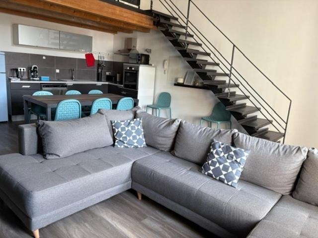 ein Wohnzimmer mit einem grauen Sofa und einer Treppe in der Unterkunft Loft-style apartment, Pierrelatte in Pierrelatte