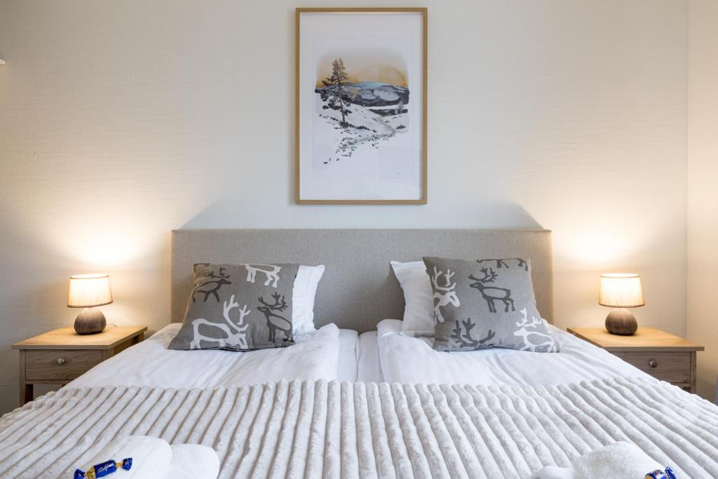 a bedroom with a white bed with two lamps at RIVER VIEW CITY NEST - Nordic Apartment With Views in Rovaniemi