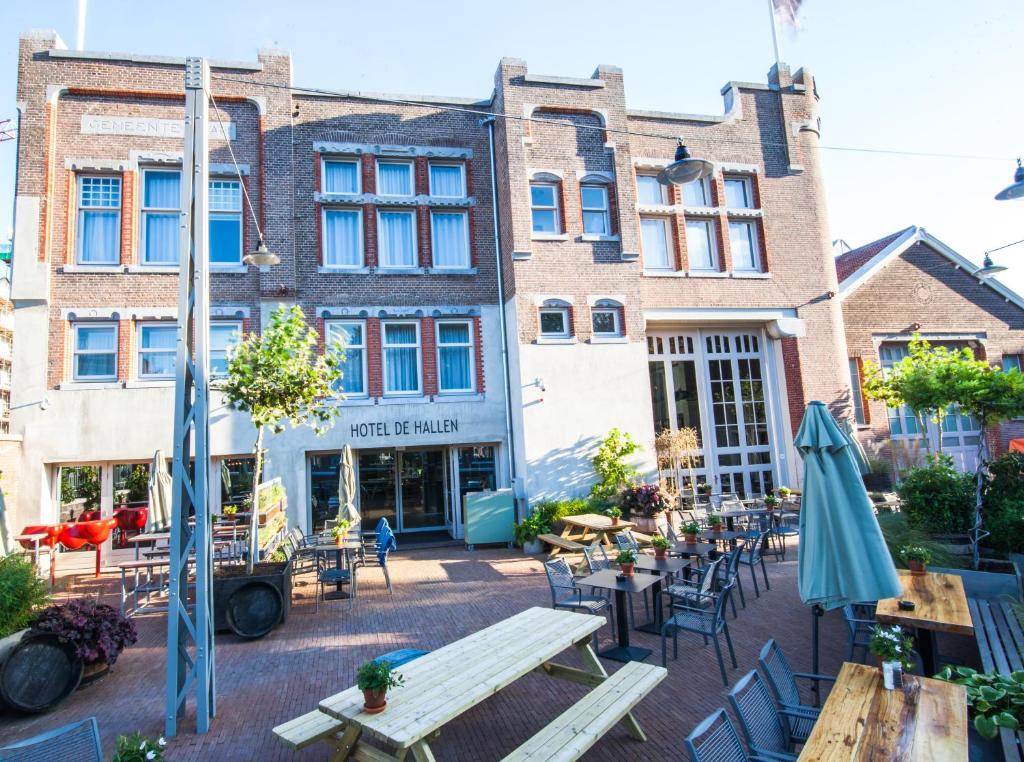 a patio with tables and chairs in front of buildings at Hotel De Hallen in Amsterdam
