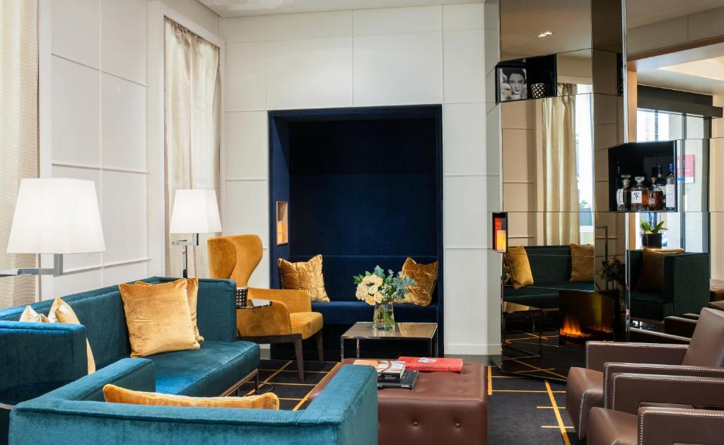 a living room with blue couches and chairs at Hotel Opéra Richepanse in Paris