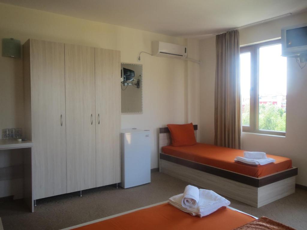 a small room with a bed and a refrigerator at Family Hotel Golden Lion in Primorsko