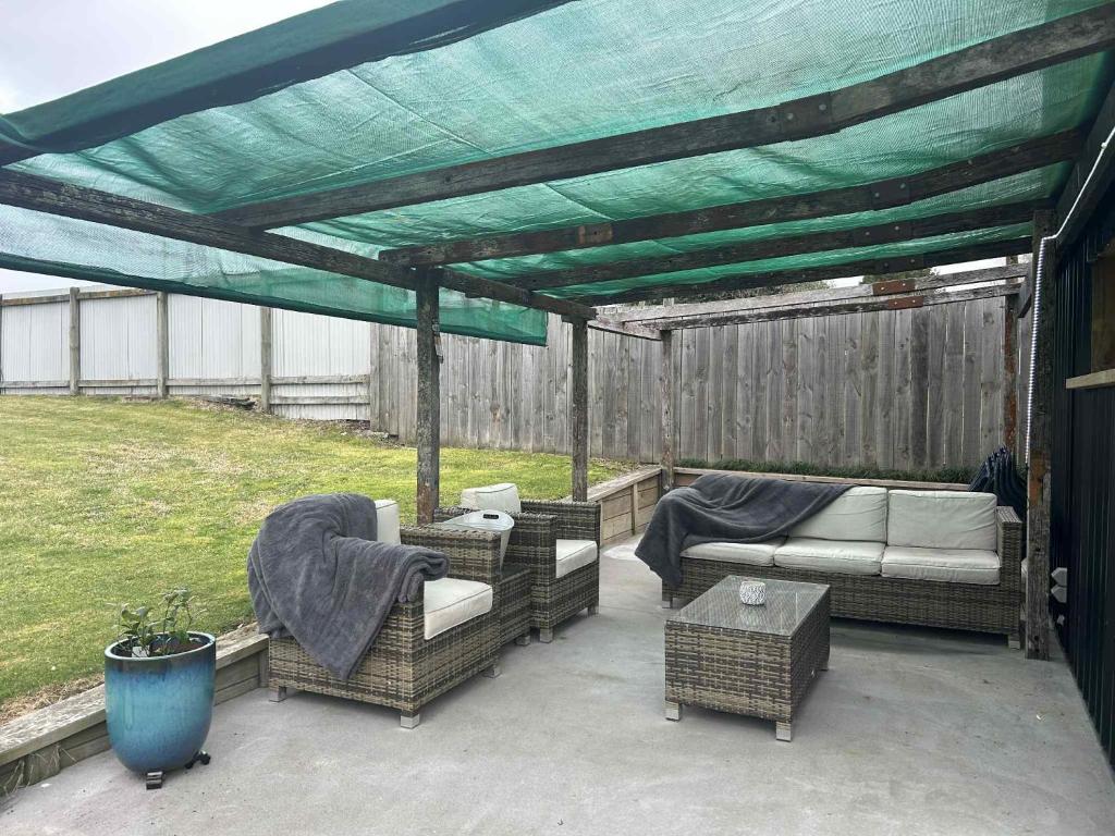 une pergola avec des canapés et des chaises sur une terrasse dans l'établissement Lake Maraetai Escape, à Mangakino