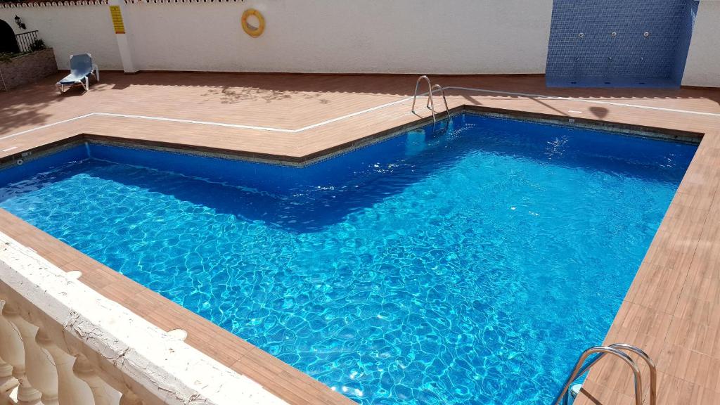una gran piscina azul con suelo de madera en Apartment Club San Antonio, en Torremolinos