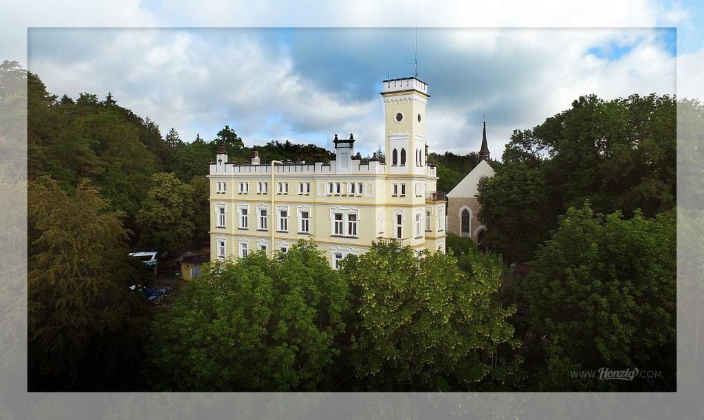 un edificio blanco con una torre de reloj encima en Hotel Štekl - Hrubá Skála en Hrubá Skála