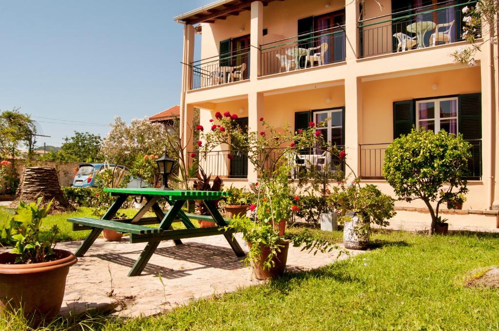 a green picnic table in front of a house at Maria's Apartments in Kavos