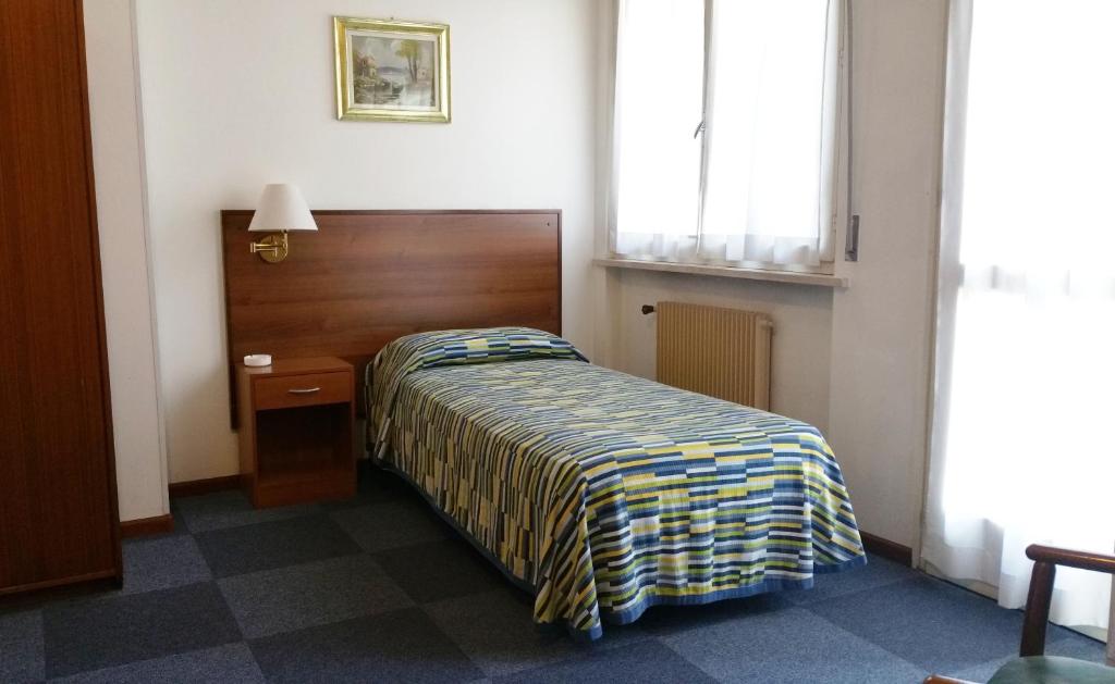 a small bedroom with a bed and a window at Hotel Capri in Pasian di Prato