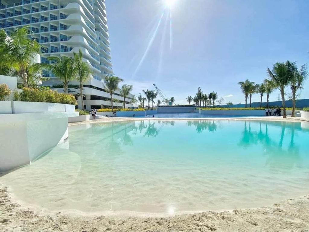 a large swimming pool with palm trees and a building at Modern Elegance Escape in Azure North Bali Tower near Malls, Airport and NLEX in San Fernando