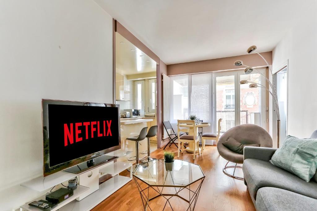 a living room with a tv with the netflix sign on it at Appartement Quartier Arc de Triomphe Free Netflix in Paris