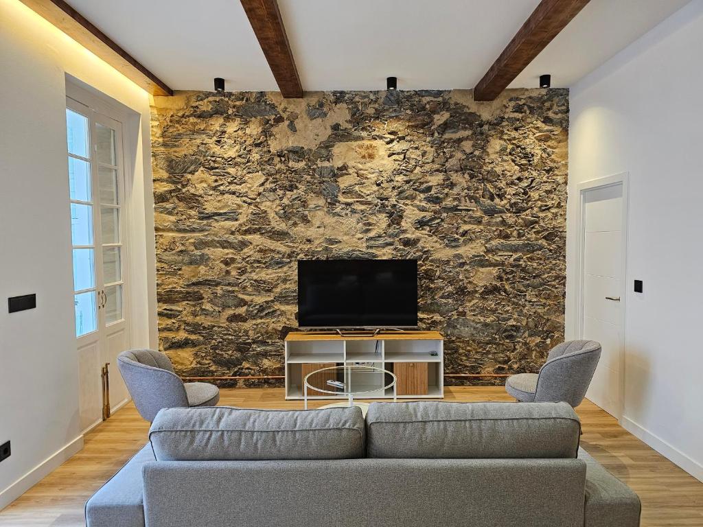 a living room with a couch and a tv on a wall at Apartamento Plaza de Armas in Ferrol
