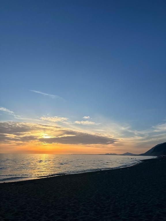 a beach with the sun setting over the water at Niko Apartaments Shengjin in Shëngjin