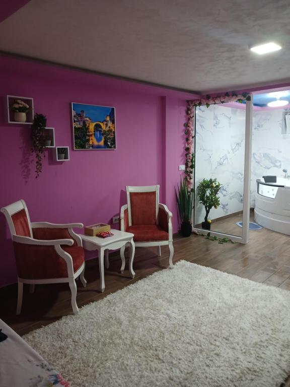 a living room with purple walls and two chairs and a table at Apartman IN Pančevo in Pančevo
