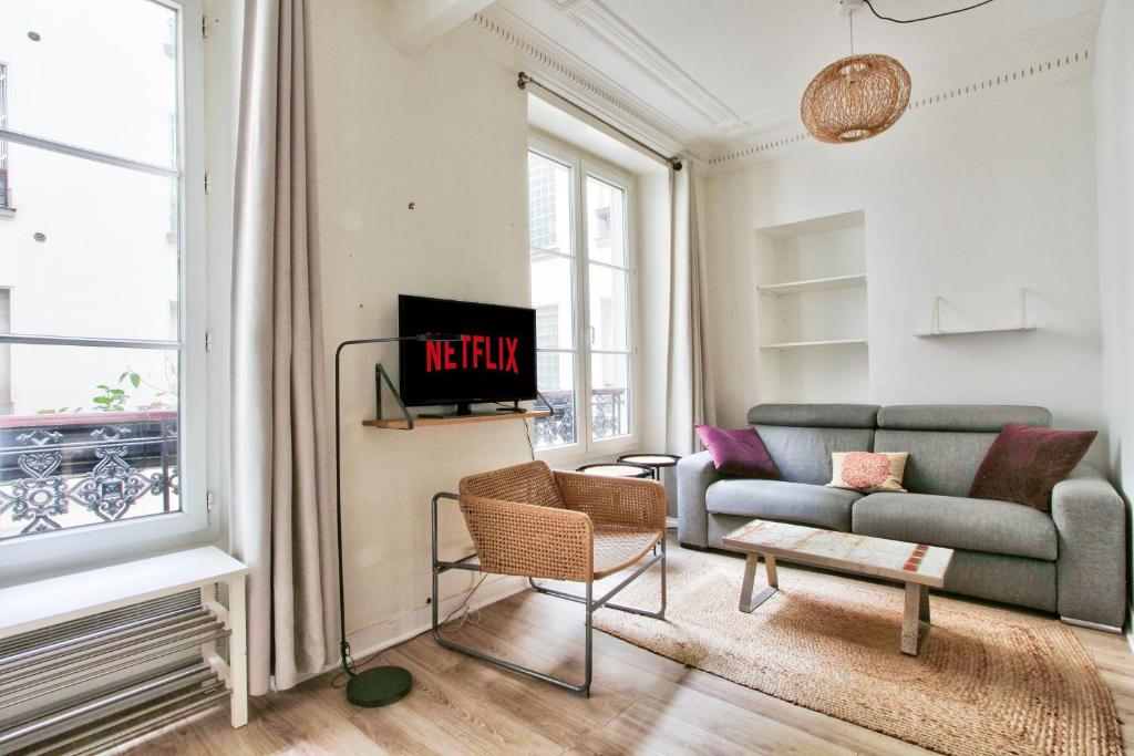 Una sala de estar con un sofá y un televisor. en Appartement Quartier Hotel de Ville Free Netflix, en París