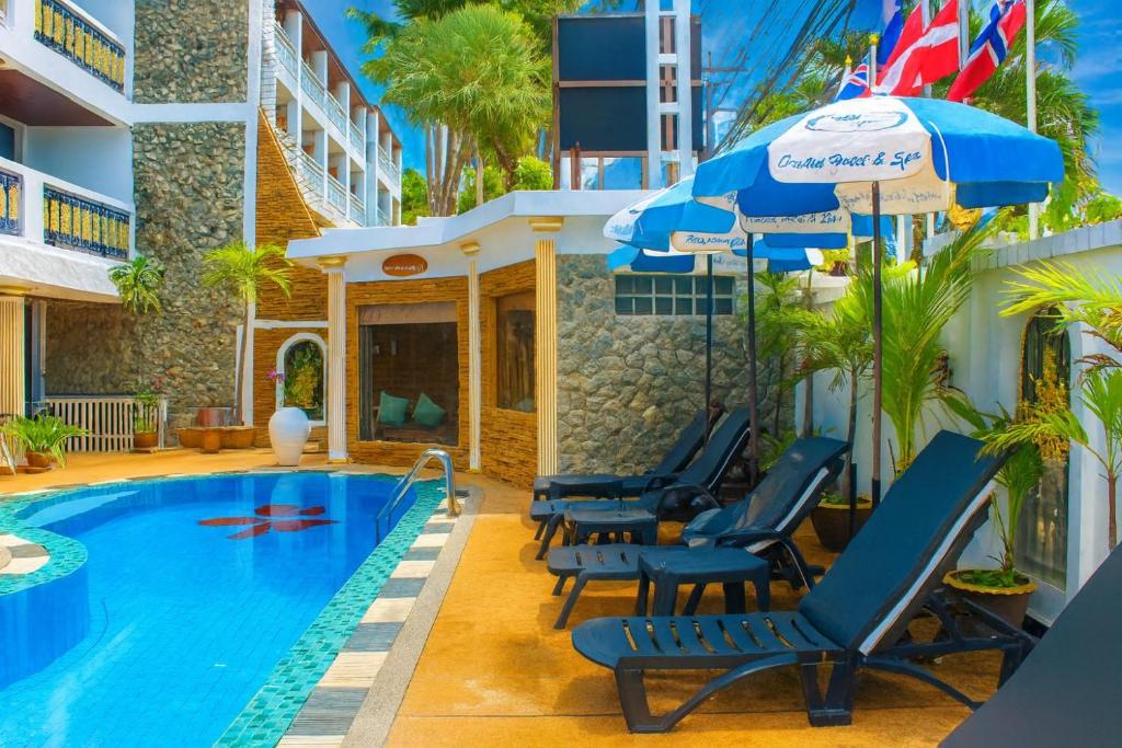 ein Resortpool mit Stühlen und einem Sonnenschirm in der Unterkunft Orchid Hotel and Spa Kalim Bay in Patong Beach