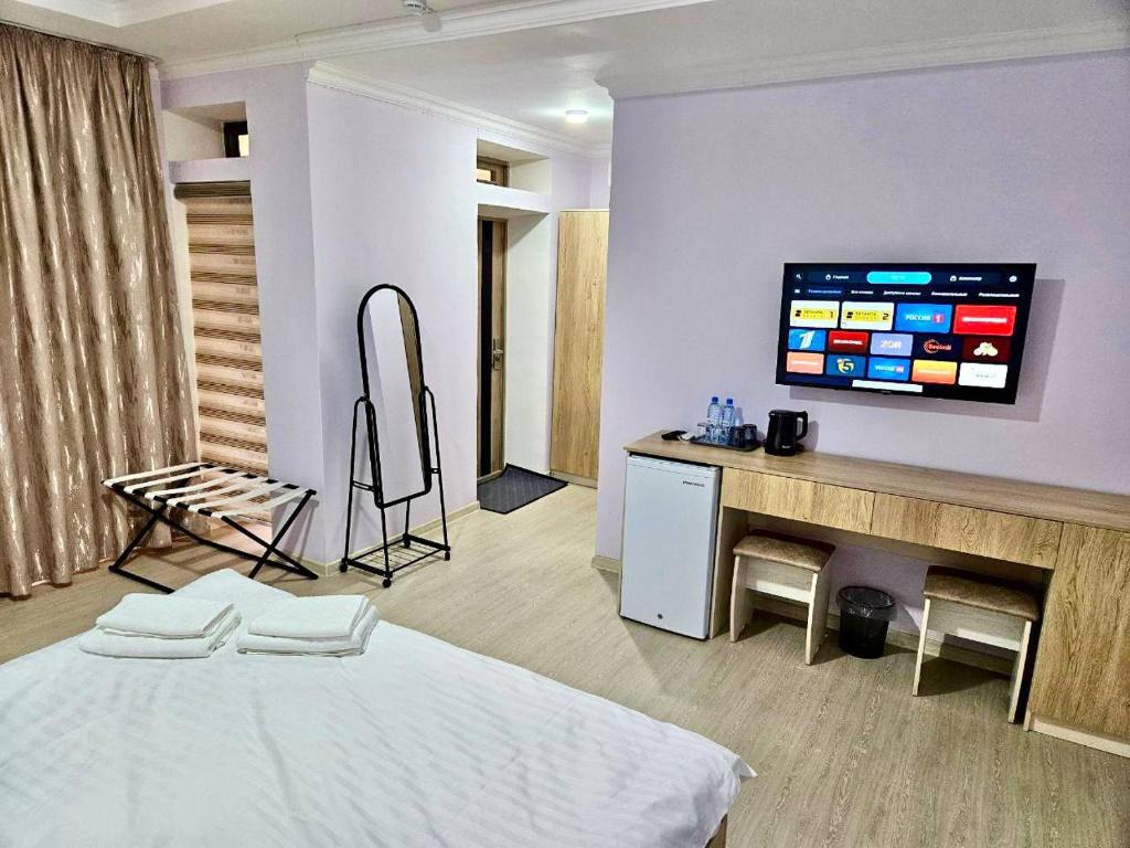Una habitación con una cama y un televisor en una pared. en Sokin Palace, en Bukhara