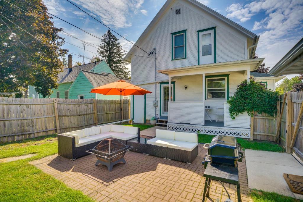 a patio with a couch and an umbrella and a table at 3 Mi to Road America Spacious Elkhart Lake Home! in Elkhart Lake