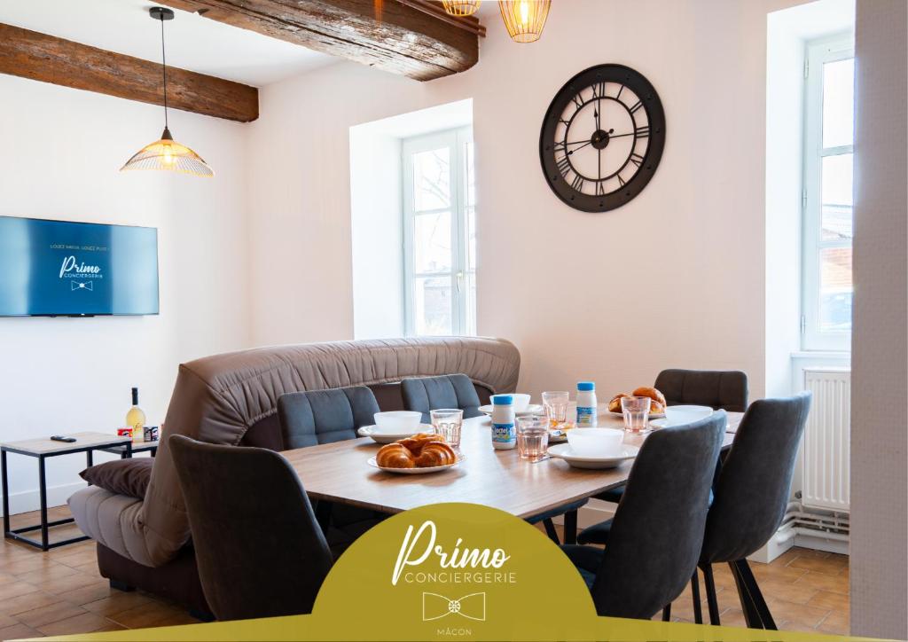 a dining room with a table and a clock on the wall at La Pause Péronnaise - Maison de ville en coeur de village in Péronne