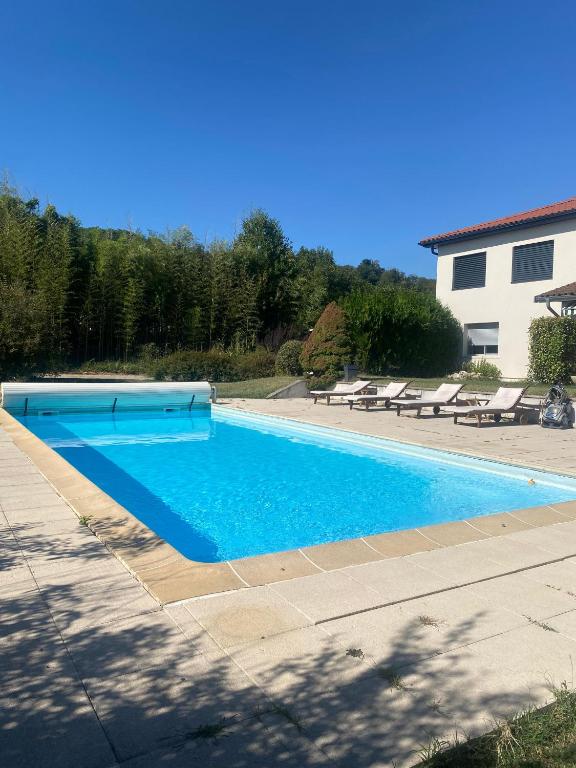 a large blue swimming pool next to a house at Charmante Maisonnette au calme, proche de Lyon in Dagneux