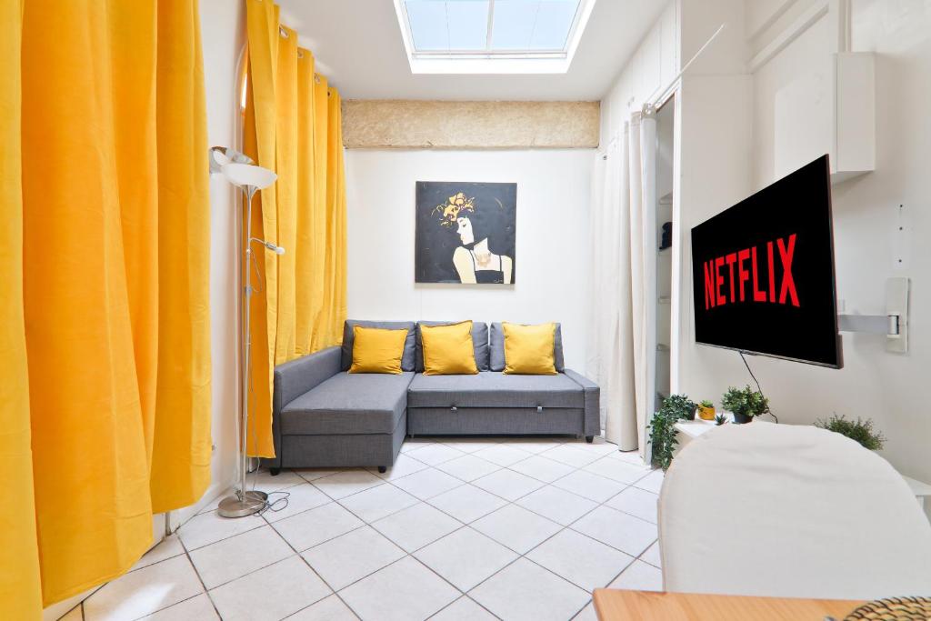 a living room with yellow curtains and a couch at Studio Appartement Quartier Musée du Louvre 3 Free Netflix in Paris