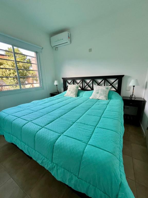 a large bed with a blue comforter in a bedroom at Granville in Valeria del Mar