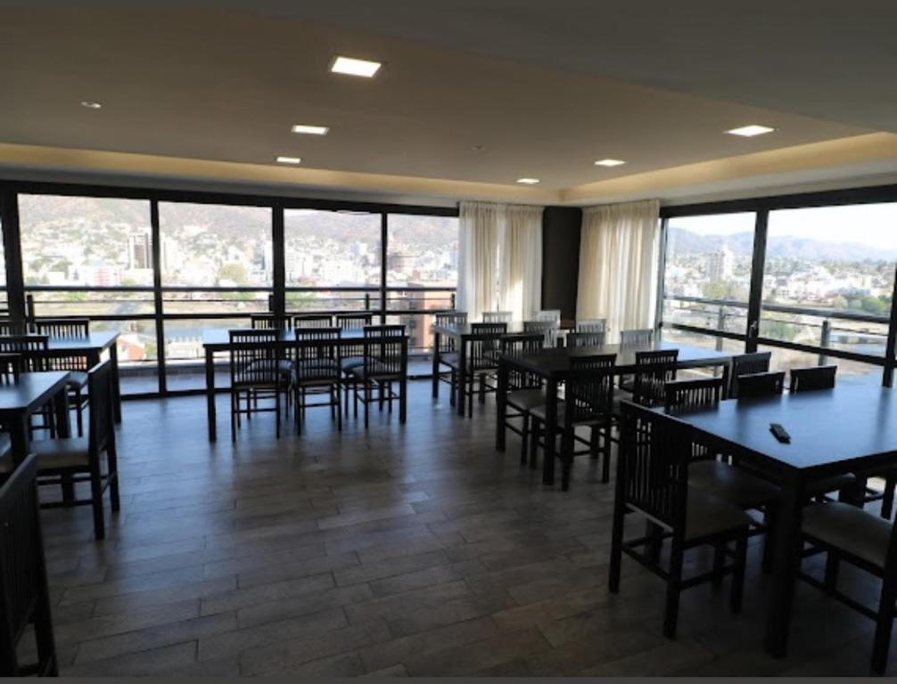 a restaurant with tables and chairs and large windows at Departamento centro Carlos Paz con pileta in Villa Carlos Paz