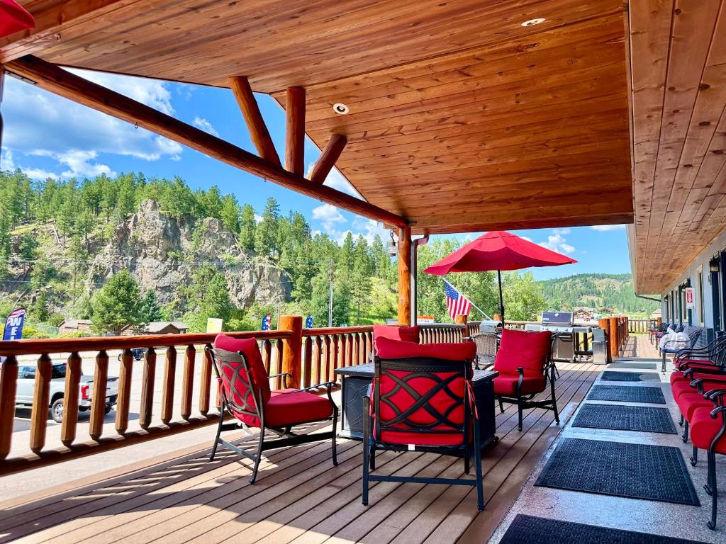 a deck with chairs and a table and an umbrella at Mountain View Lodge & Cabins in Hill City