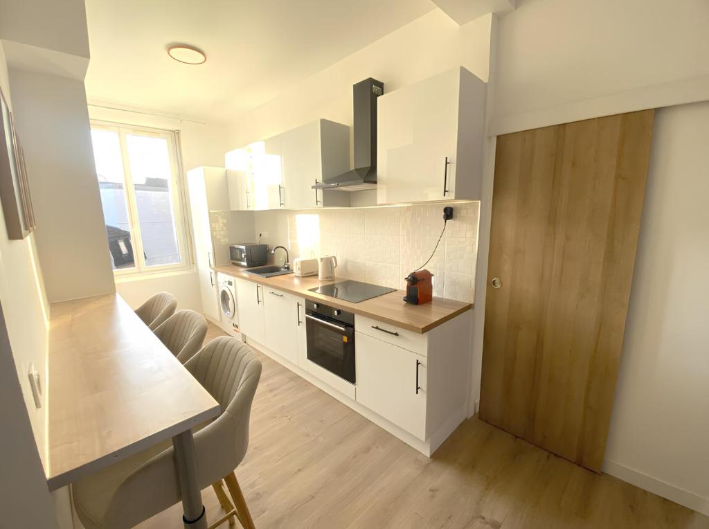 a kitchen with white cabinets and a table and chairs at Coeur de ville - Appartement 2 chambres in Amiens