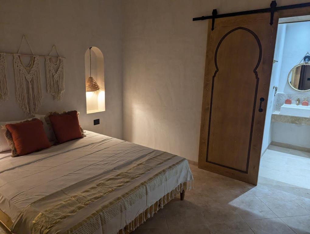 a bedroom with a large bed with a wooden door at Magnifique villa typique avec piscine privée in El Guecheïne