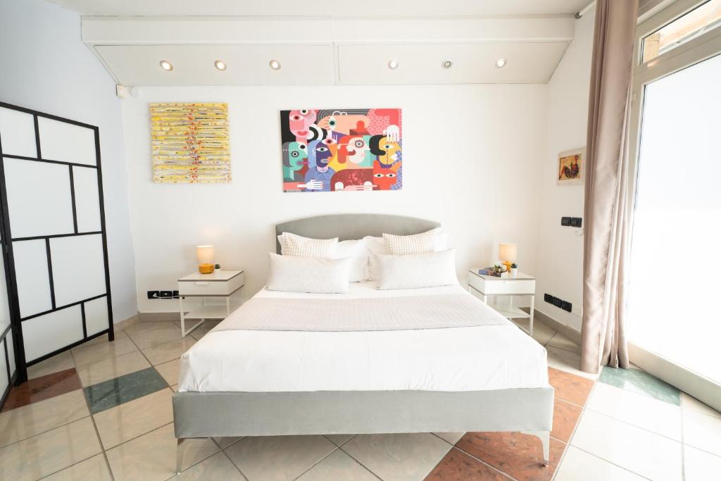 a white bedroom with a large bed and two tables at Amarin Pisa Room in Pisa