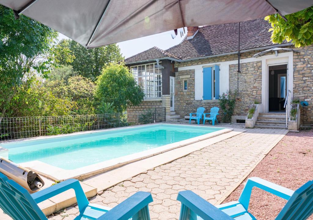 a swimming pool with blue chairs and an umbrella at Le Clos Poncétys - Villa avec Piscine in Davayé