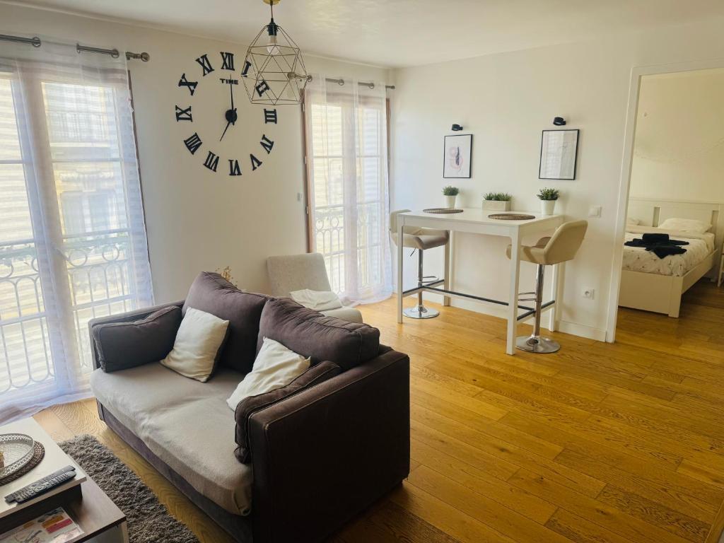 a living room with a couch and a clock on the wall at Cosy Appart Rueil - 50m2 Parking Souterrain - proche Paris - Business et loisir in Rueil-Malmaison