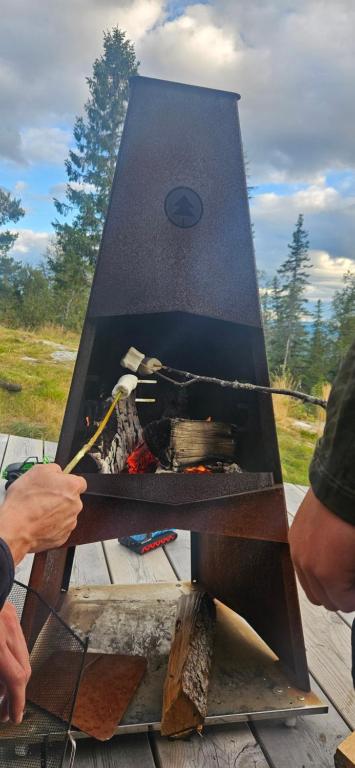 Ein Mann kocht über einem Feuer im Grill in der Unterkunft Traditional cabin at Norefjell in Surteberg