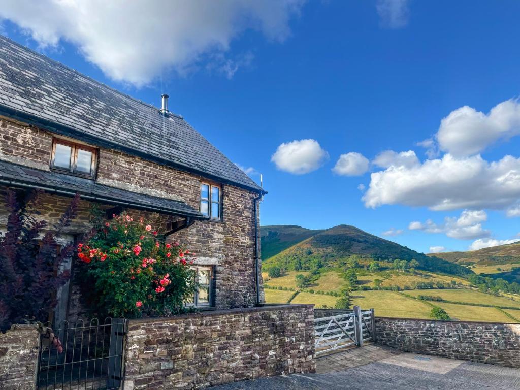 a stone house with a flowering bush on the side of it at Mountain View Farm Cottage in Crickhowell