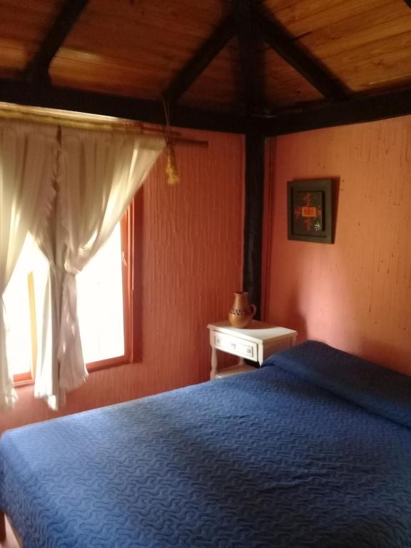 Un dormitorio con una cama azul y una ventana. en Complejo LOS PINOS, en La Porteña