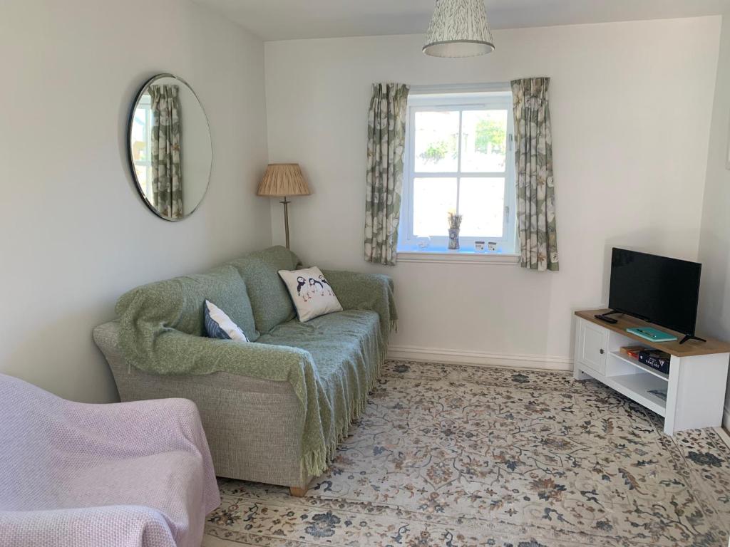 a living room with a couch and a television at May Cottage in Anstruther