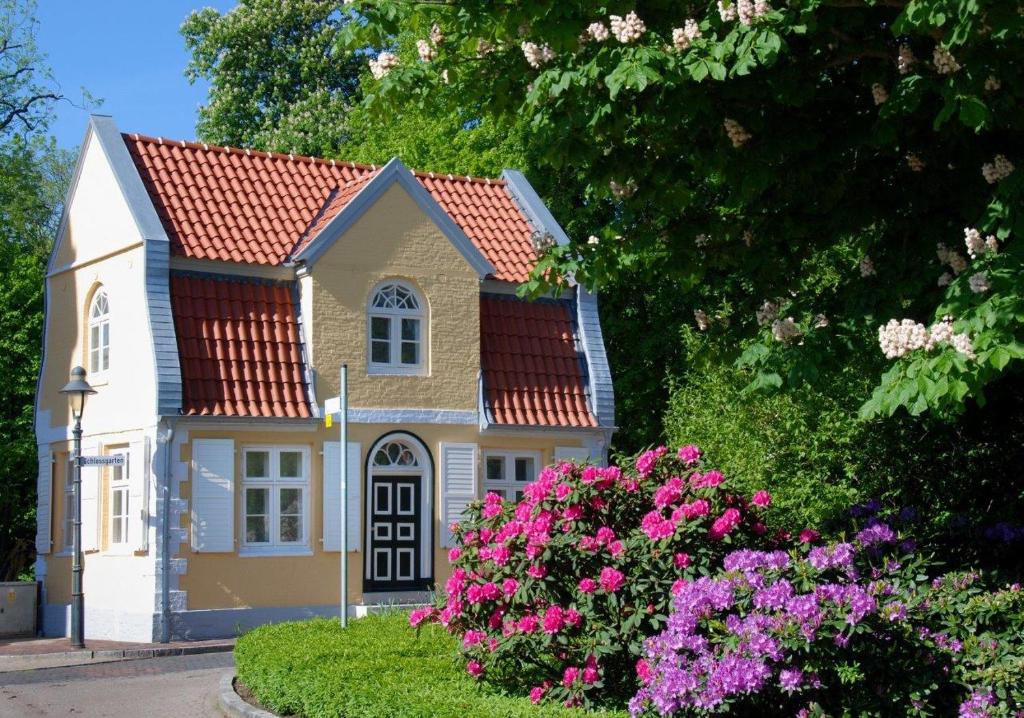 una pequeña casa con flores rosas en el patio en Gärtnerhaus en Cuxhaven
