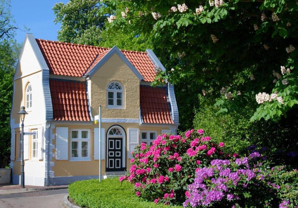 uma pequena casa com flores cor-de-rosa no quintal em Gärtnerhaus em Cuxhaven