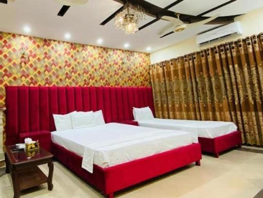 a bedroom with two beds and a red wall at Couple Friendly Guest House in Karachi