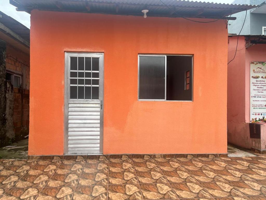 an orange building with a door and a window at Kitnet COP30 in Ananindeua