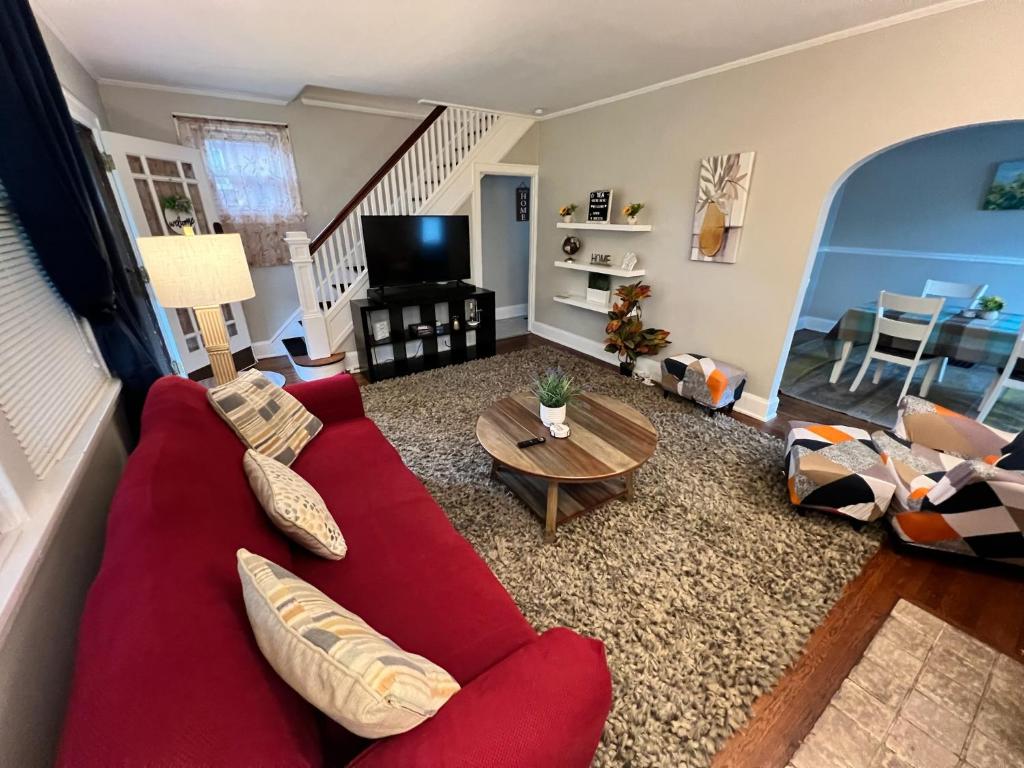 a living room with a red couch and a table at Comfy Cozy Bungalow Suite 2 10 min from Downtown in Cincinnati