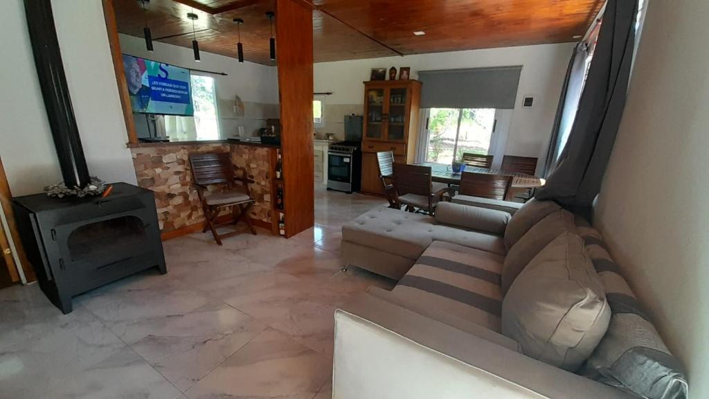 Una sala de estar con un sofá y una estufa. en La casita del bosque, en Valeria del Mar