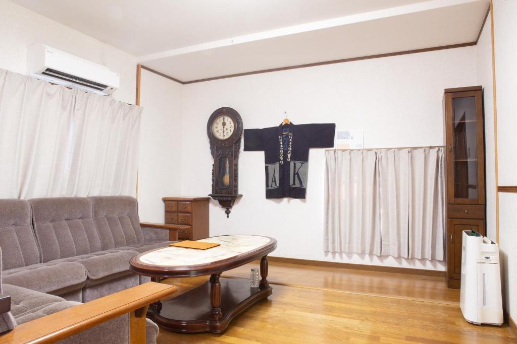 a living room with a couch and a clock on the wall at 中通りハウス in Zentsuji
