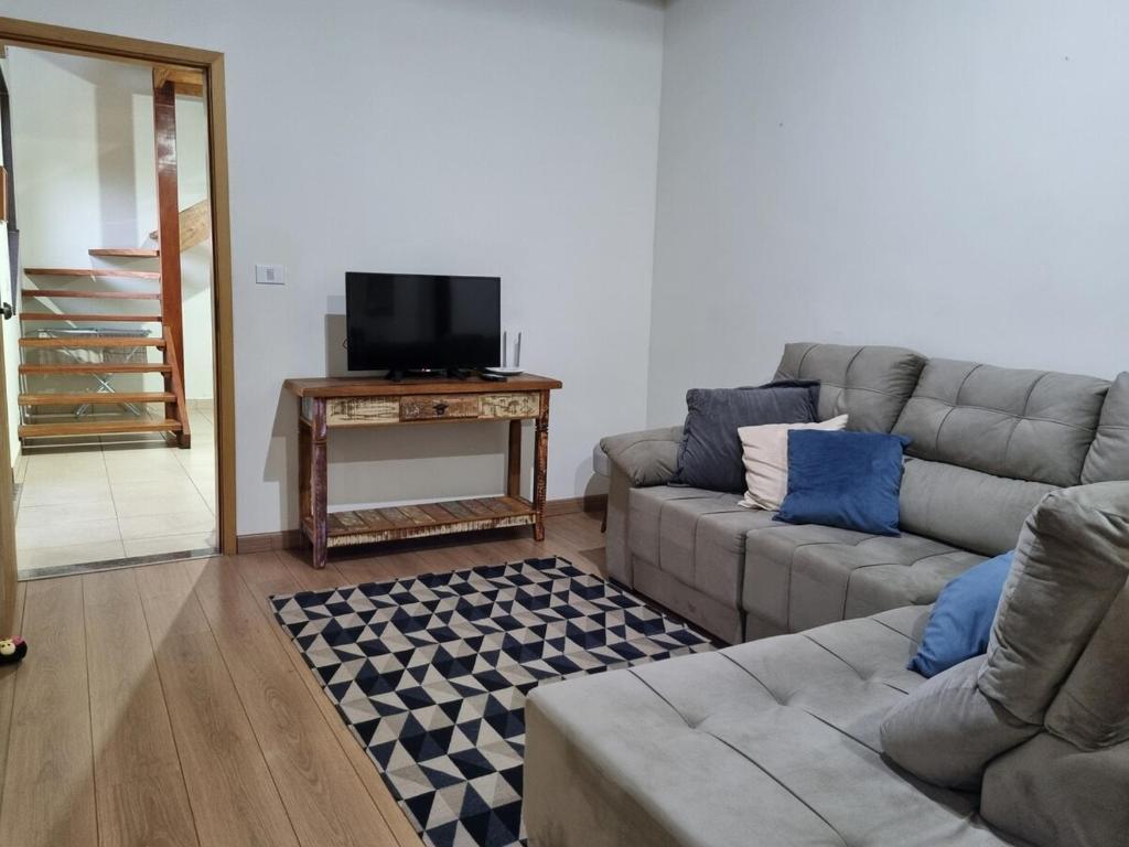 un salon avec un canapé et une télévision dans l'établissement Sítio São João, à Córrego do Bom Jesus