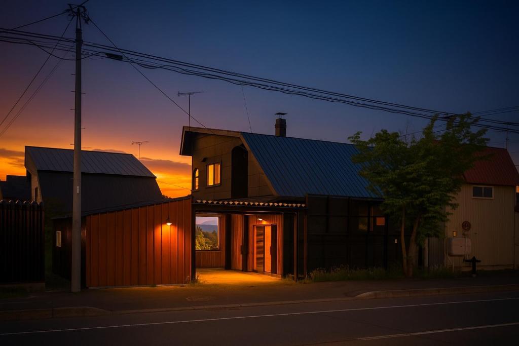 ein Haus in einer Straße mit dem Sonnenuntergang im Hintergrund in der Unterkunft Retaruke-レタルケ- in Biei