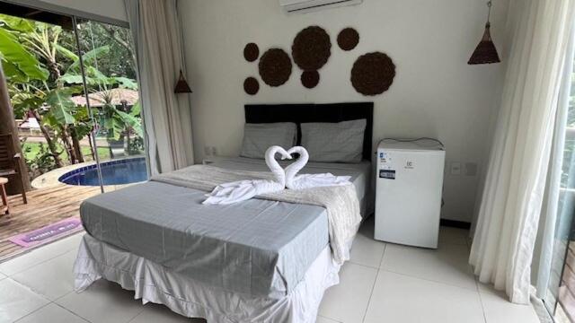 una camera da letto con un letto con due cigni sopra di Villas Pratagy- Jambu 2-Bangalô Master a Maceió
