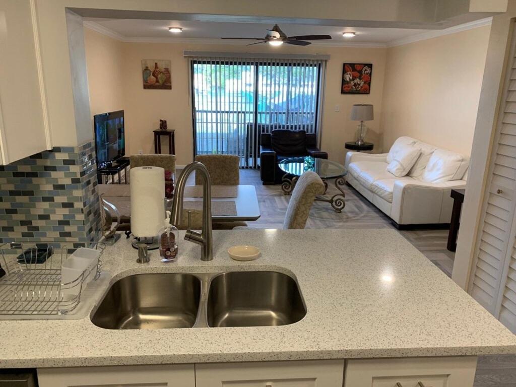 a kitchen with a sink and a living room at Fully furnished Condo in Deerfield Beach