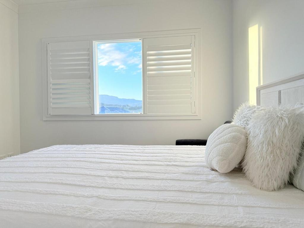 a bedroom with a white bed with a window at Serene Escape in Tullimbar