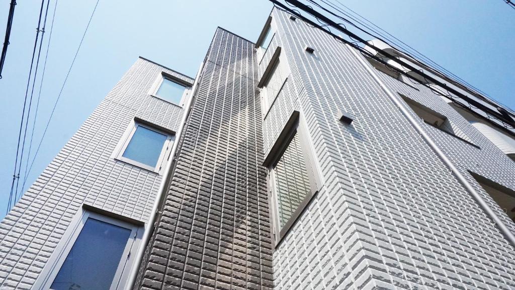 un edificio alto de ladrillo con ventanas en un lateral en Poly Hostel Osaka, en Osaka